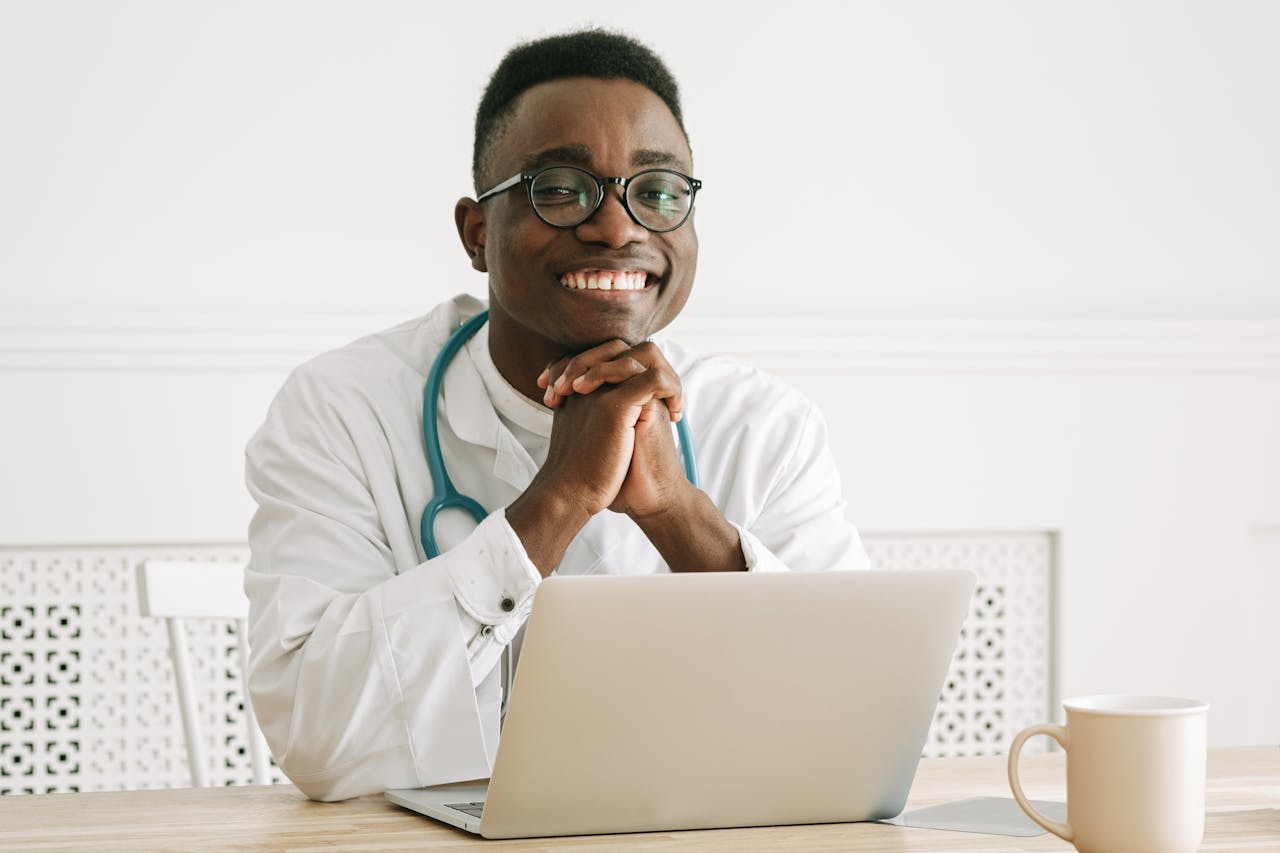Happy doctor wearing eyeglasses and stethoscope smiling confidently at his workplace.