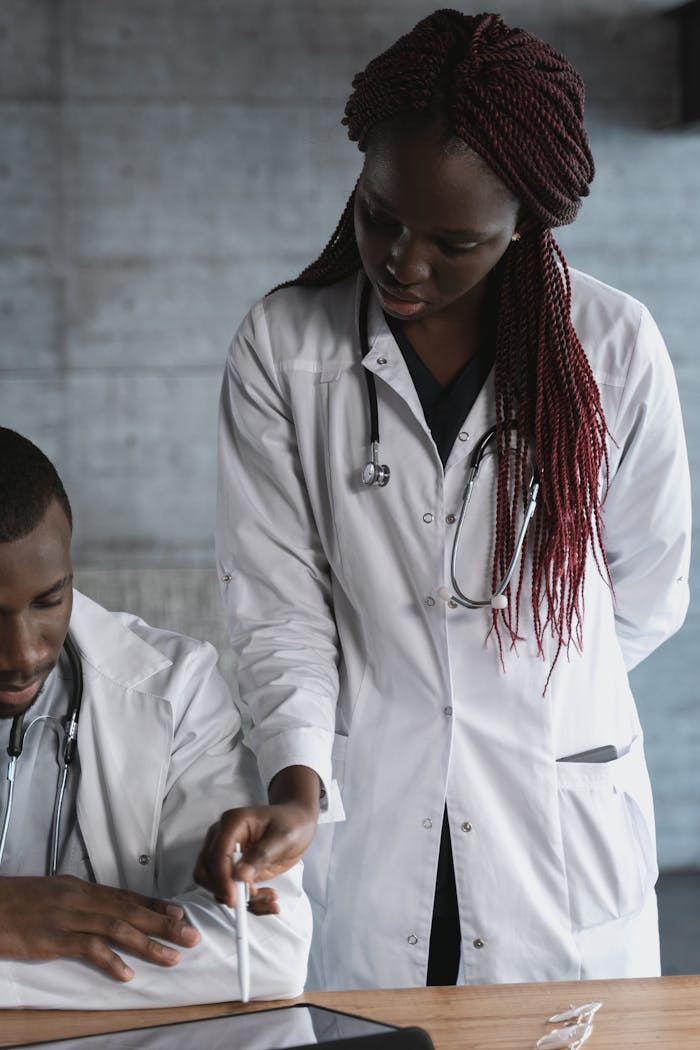 Black male and female doctors collaborating in a medical clinic with a tablet.