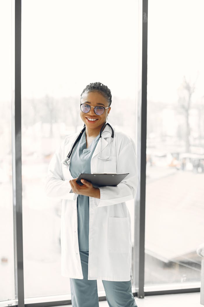 Smiling female healthcare professional with clipboard and stethoscope indoors.